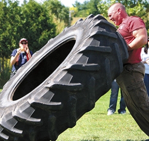 Man flipping a tire in the Strongman event.