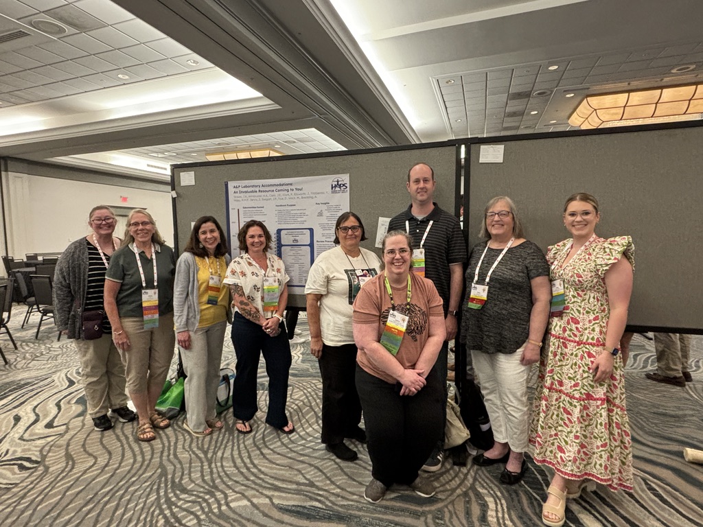 A photo of the C&I Accommodations Subcommittee. Individuals standing in front of a poster.